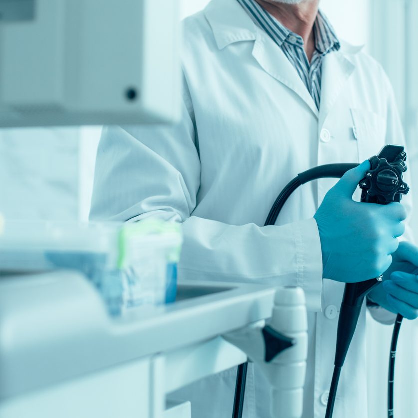 Modern endoscope in hands of experienced medical worker Cropped photo of a man in white coat and rubber gloves standing with a modern endoscope